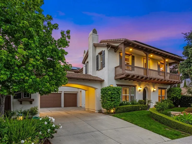 Exterior of the two-storey Mediterranean home at 3212 Corte Tamarindo in Carlsbad, CA, at dusk.